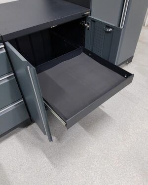 Verktygsskåp med 1 låda och dörrar grå, PRO har en öppen metalllåda med svart foder som sträcker sig från en mörkgrå enhet, mot ljust texturerat golv. Den innehåller ytterligare stängda lådor och ett högt fack.