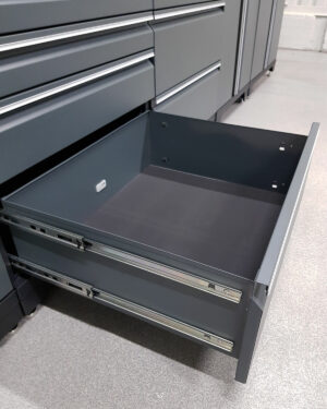 En grå metalllåda från Verktygsskåp med 5 lådor grå, PRO verktygslåda glider mjukt upp mot ett texturerat grått golv och avslöjar dess tomma utrymme med rena linjer och robust byggnad.