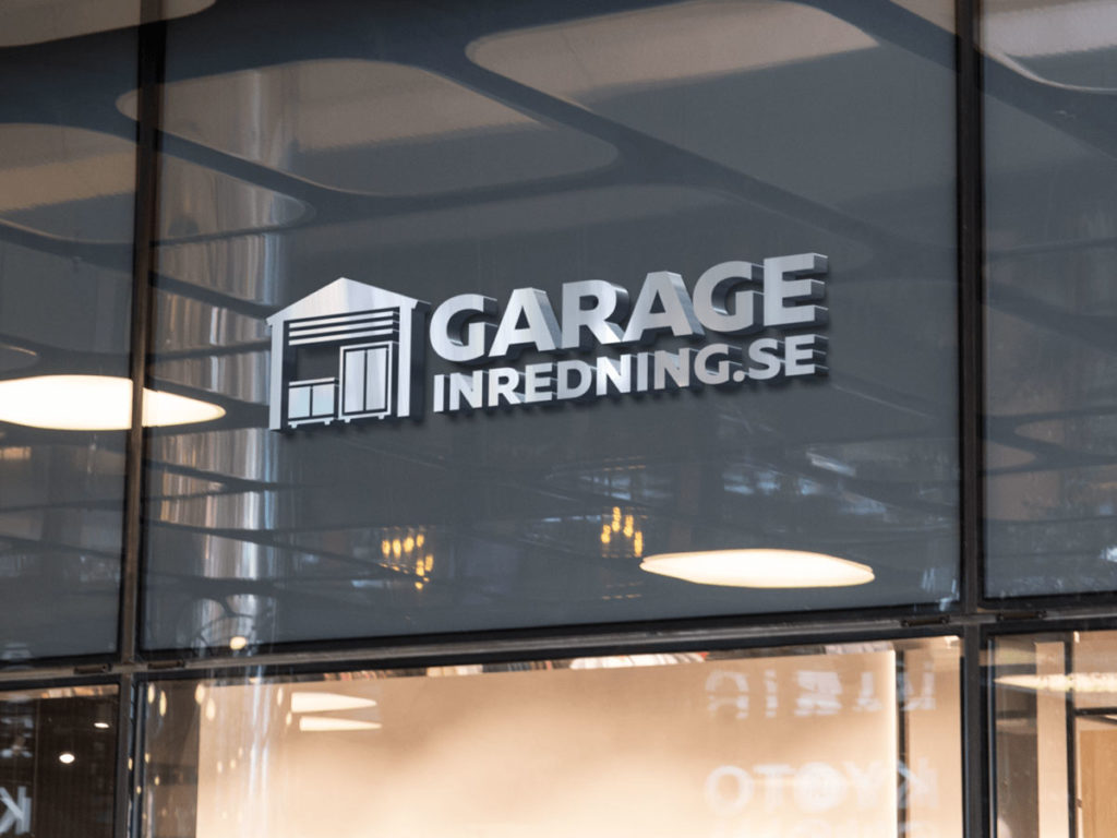 Skylt för "Garage Inredning.se" på ett glasfönster, med logotypen för en stiliserad garageport. Reflexioner av armaturer kan ses, vilket indikerar en inomhusmiljö.