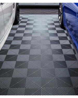 Ett garagegolv visar SWISSTRAX RIBTRAX golvplattor i Jet-Black med ett intrikat svart och grått geometriskt mönster av sammankopplade diamanter, kantad av en vit bil till vänster och en blå bil till höger.
