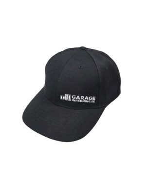 En svart snapback-keps med vit broderad text på framsidan där det står "GARAGEINREDNING.SE.