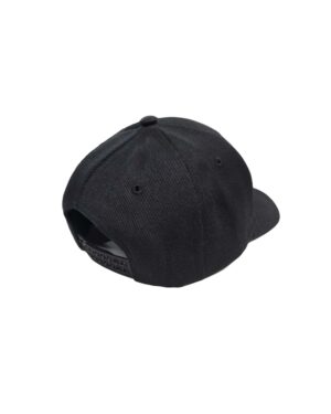 "Keps Garageinredning.se snapback svart" visas från baksidan och framhäver dess snapback-stängning för justerbar storlek och en lätt böjd brätte. Kepsen ställs mot en vanlig vit bakgrund.